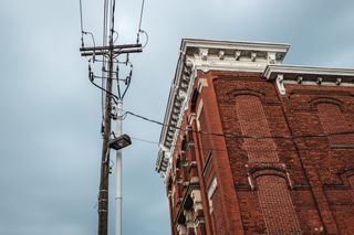 A view looking up at electrical wires and the side of a brick building