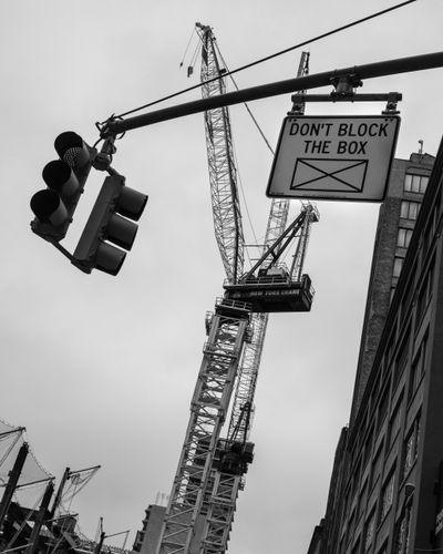 A traffic light and roadway sign with large construction crane in the background