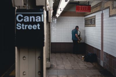 Saxophonist playing facing into corner of subway platform