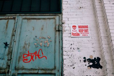 A rusty metal door next to a sign warning about rat poison