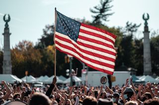 A person holds an American flag above a large gathering of people