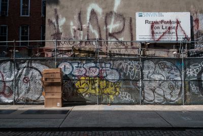 Sidewalk fence and wall covered in graffiti