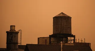 Rooftop water tower in Manhattan’s Soho neighborhood under orange-tinted sky