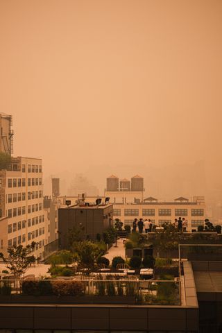 People on a building rooftop in Manhattan’s Soho neighborhood under orange-tinted sky