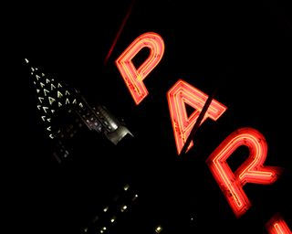 Photo of Chrysler Building with neon “Parking” sign in close foreground